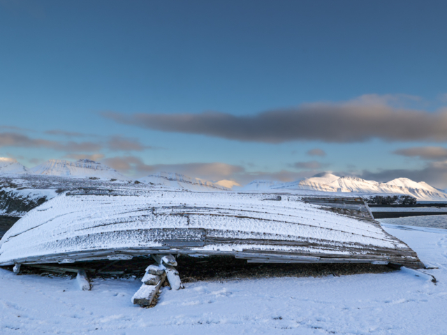 Photograph of old wooden whaling boat with distant mountains