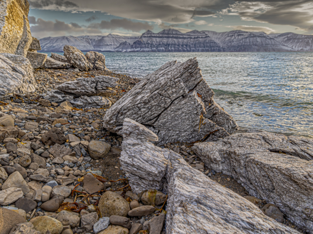 Photograph of blocks of gypsum along a shore with black and white mountains in the background