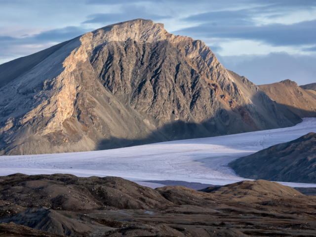 Photograph of a strange crested mountain with a glacier in front.