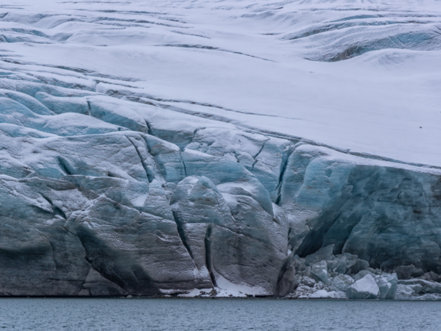Photograph of a blue soft glacier with snow on top of it