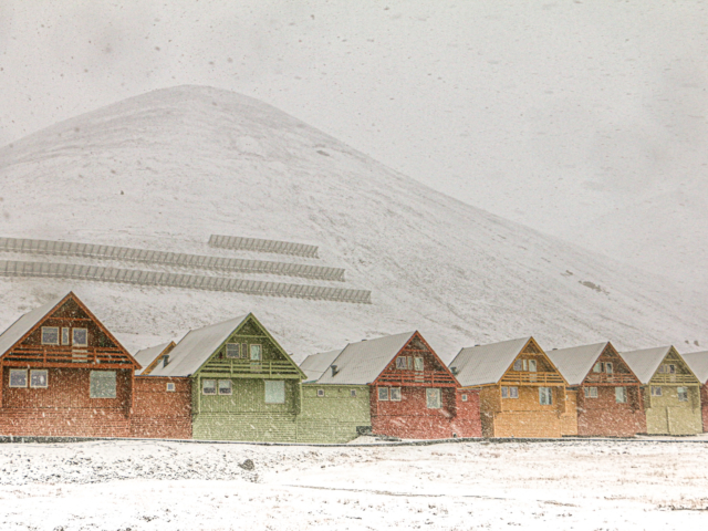 Seven Sisters of Svalbard seven colorful painted houses in Longyearbyen Svalbard in front of Sukkerrtoppen in a snowstorm