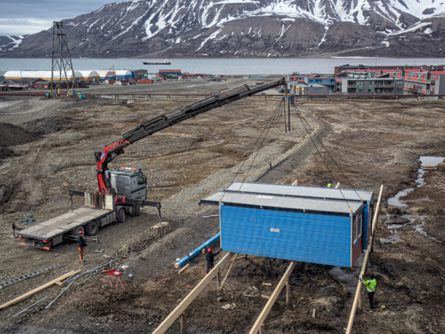 Bulding Worker Barracks Crane sets blue container housing down for workers' barracks in Longyearbyen Svalbard