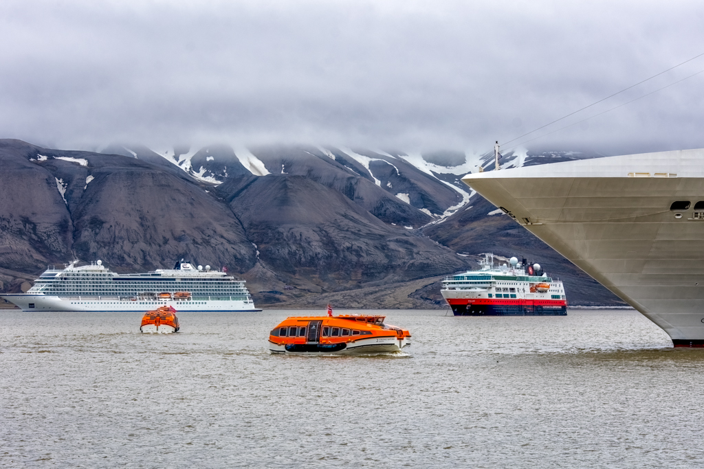 Cruise Ship Arrival photograph of three cruise ships and tenders in front of mountains
