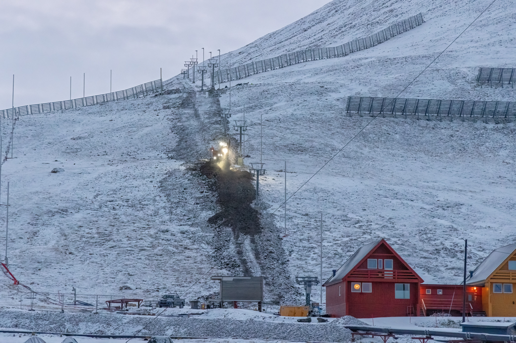 Building a Ski Slope Photograph of a mountain with machinery and dirt in front of one of Longyearbyen historic orange pointy houses
