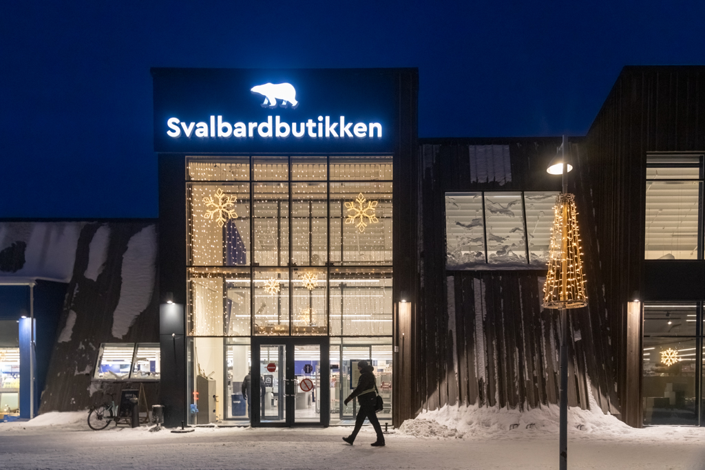 Svalbardbutikken Photograph of a store front at night with a lit up polar bear on top