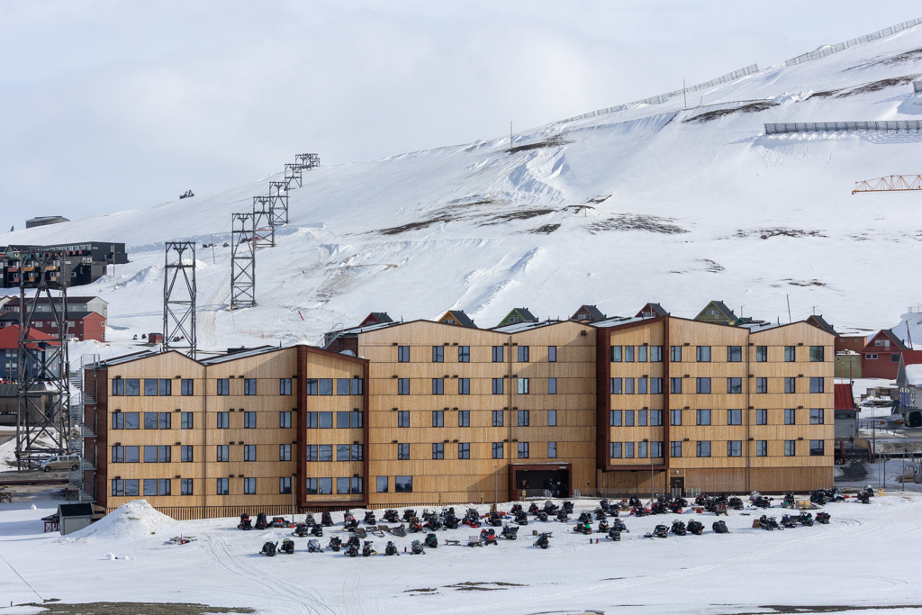 UNIS Dormitories Photograph of wooden buildings against a snowy mountain